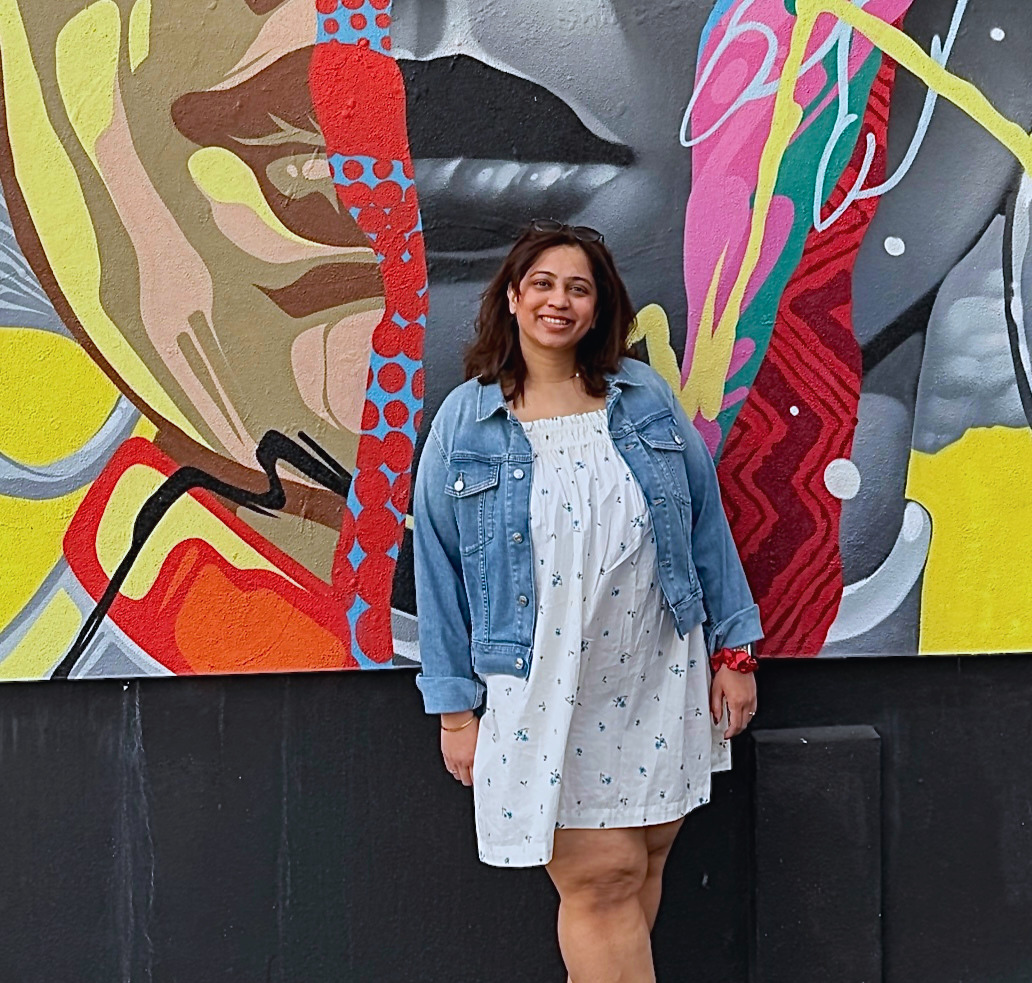 Ankita Gawde standing in front of a colourful mural